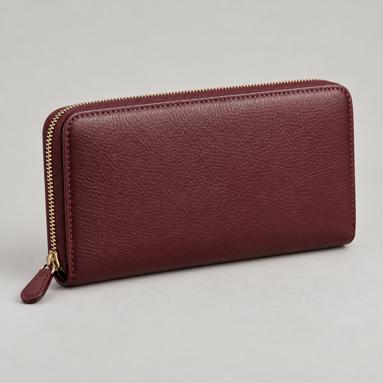 Bordeaux Zip Wallet: Long rectangular wallet with a wraparound zip and a small matching pull tab. Illustrative design reference.
